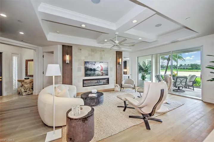 Main living area with Limestone feature wall, built in television, electric fireplace, coffered ceiling, recessed lights, ceiling fan