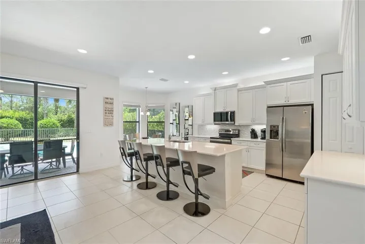 Kitchen with appliances with stainless steel finishes, backsplash, light countertops, a kitchen breakfast bar, and a kitchen island