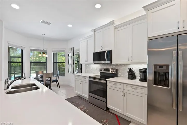 Kitchen featuring appliances with stainless steel finishes, recessed lighting, light countertops, backsplash, and hanging light fixtures