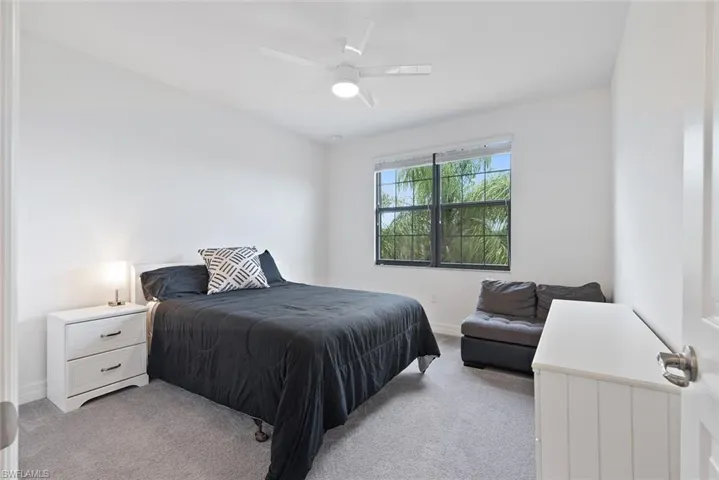 Bedroom featuring light carpet, ceiling fan, and vaulted ceiling