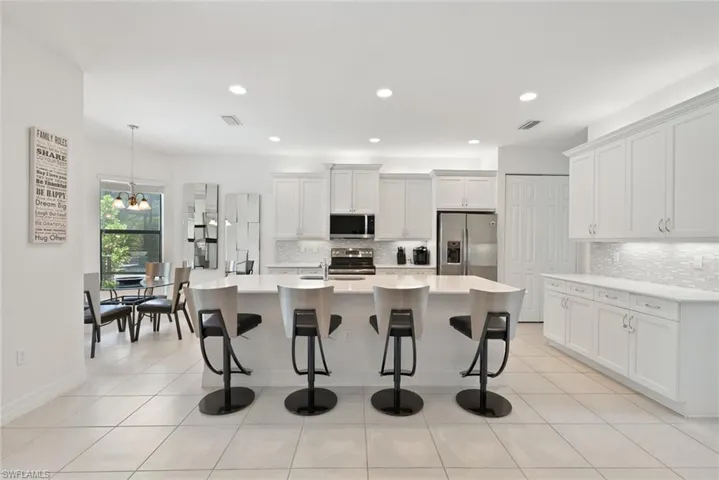 Kitchen featuring stainless steel appliances, tasteful backsplash, a breakfast bar, light countertops, and recessed lighting