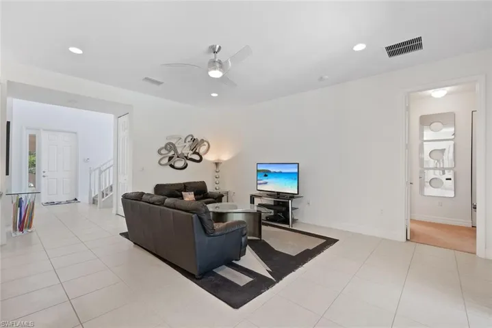 Living room featuring a ceiling fan, light tile patterned flooring, recessed lighting, and stairs