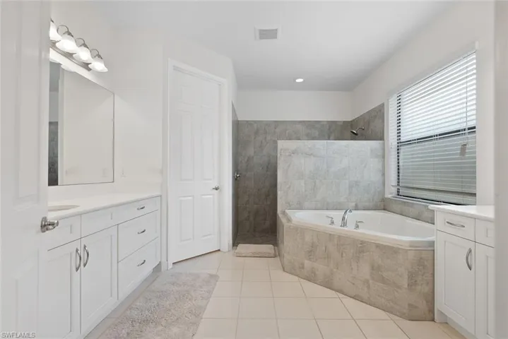 Bathroom with vanity, a walk in shower, tile patterned flooring, and a garden tub
