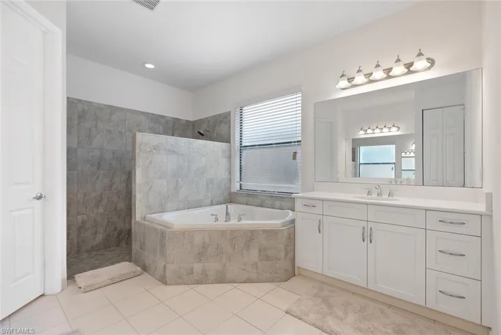 Full bath featuring vanity, walk in shower, a bath, and tile patterned floors