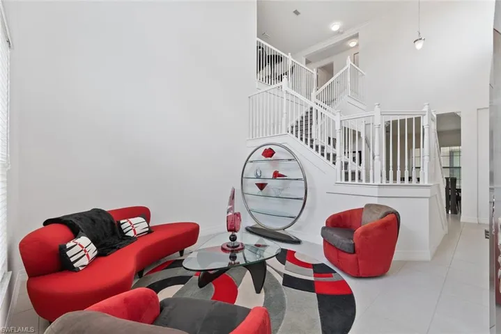 Tiled living area featuring stairway, a high ceiling, and crown molding