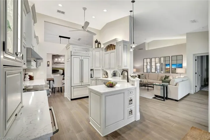 Kitchen featuring paneled fridge, open floor plan, light stone counters, a peninsula, and hanging light fixtures