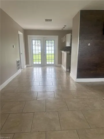 Unfurnished living room featuring french doors and tile patterned flooring