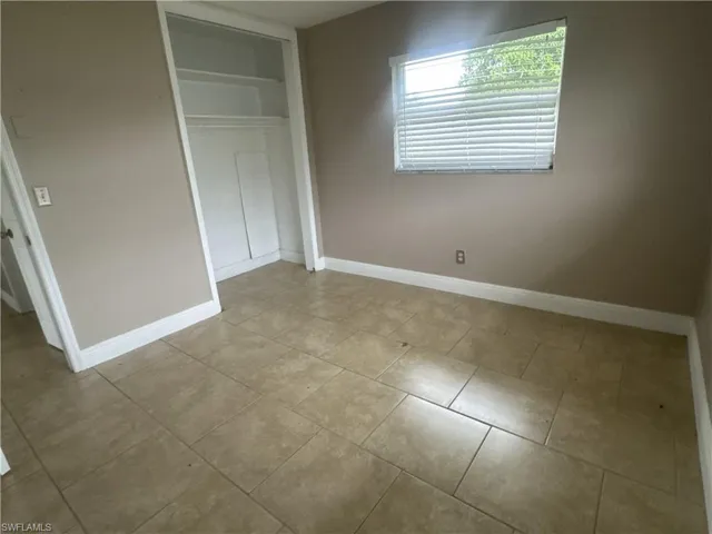 Laundry room with washer and clothes dryer and light tile patterned floors