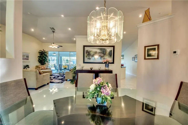 Dining space with ceiling fan with notable chandelier, vaulted ceiling, and light tile patterned floors
