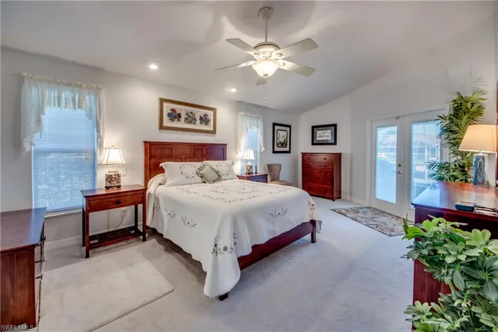 Bedroom with lofted ceiling, ceiling fan, access to outside, light colored carpet, and french doors