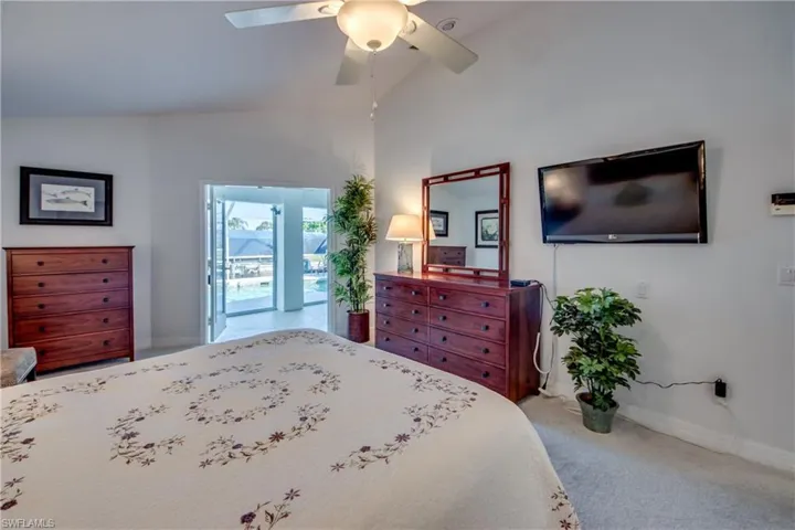 Carpeted bedroom featuring ceiling fan and vaulted ceiling