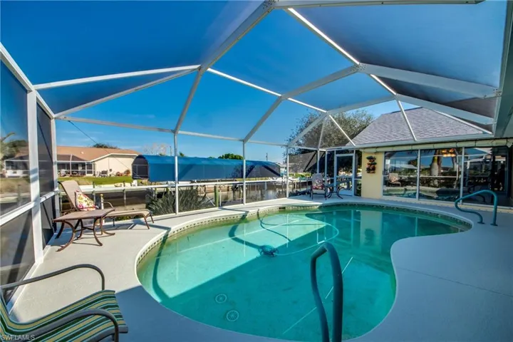 View of pool featuring a patio area and glass enclosure