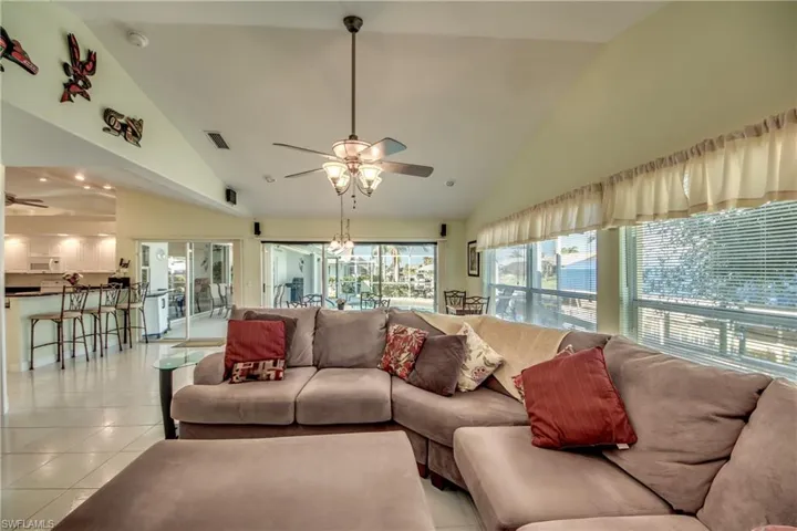 Tiled living room with ceiling fan and high vaulted ceiling