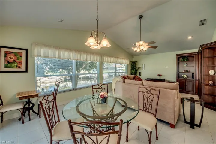 Tiled dining space featuring lofted ceiling and ceiling fan with notable chandelier