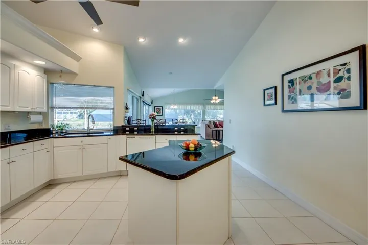 Kitchen featuring white dishwasher, sink, light tile patterned floors, and white cabinets
