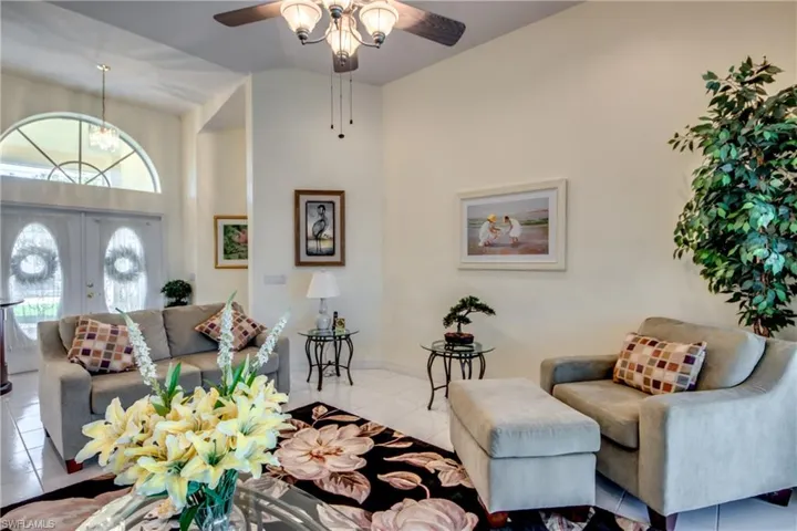 Tiled living room with a towering ceiling, ceiling fan, and french doors