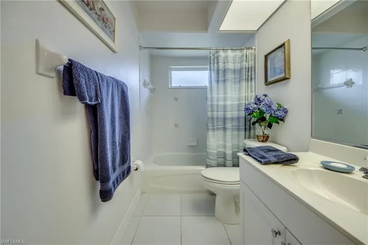 Full bathroom with shower / tub combo with curtain, tile patterned floors, toilet, and vanity