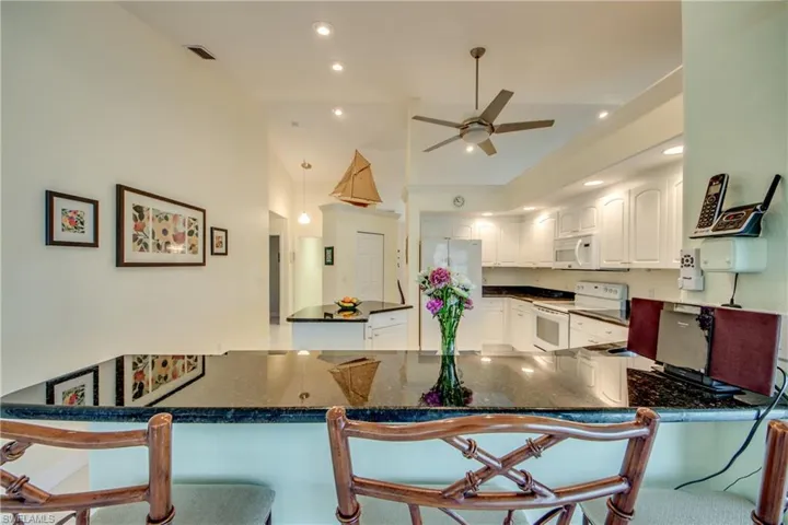 Kitchen featuring a kitchen breakfast bar, white cabinets, white appliances, and kitchen peninsula