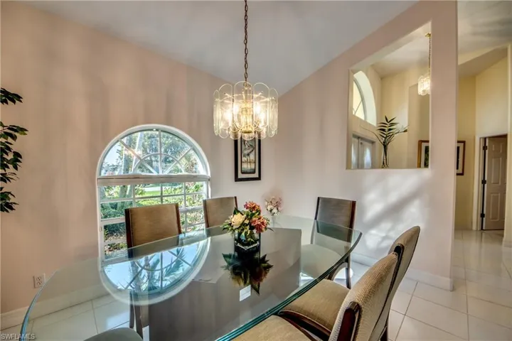 Tiled dining space featuring vaulted ceiling and a notable chandelier