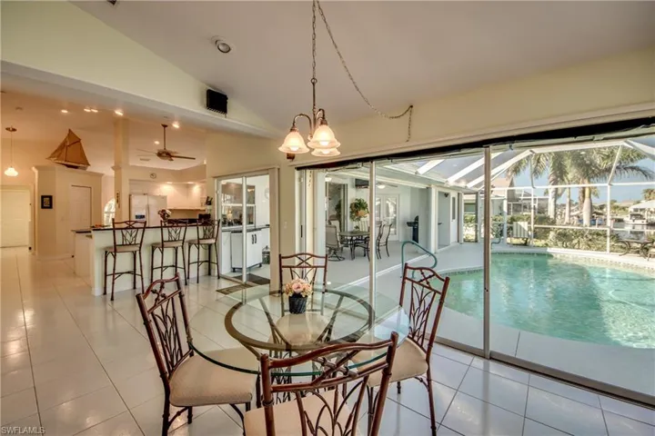 Dining area with high vaulted ceiling, ceiling fan, and light tile patterned flooring