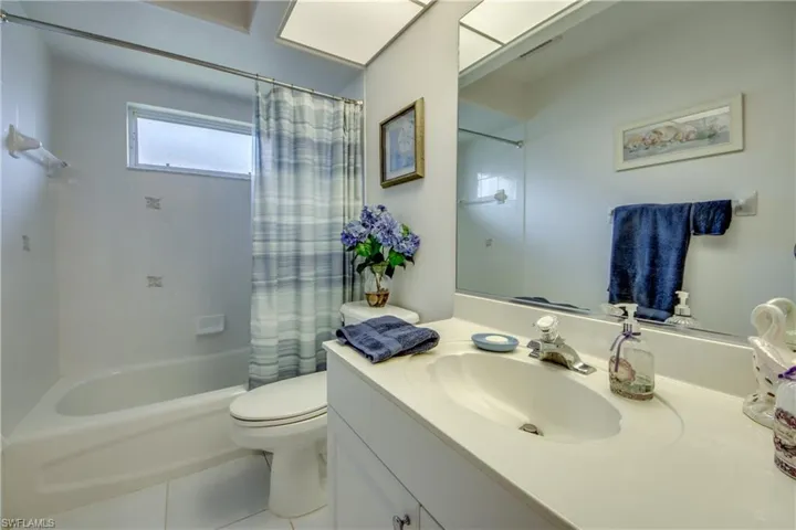 Full bathroom with shower / bath combination with curtain, tile patterned floors, vanity, and toilet