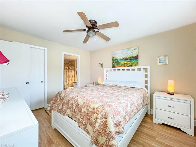 Bedroom with ensuite bath, ceiling fan, and light hardwood / wood-style flooring