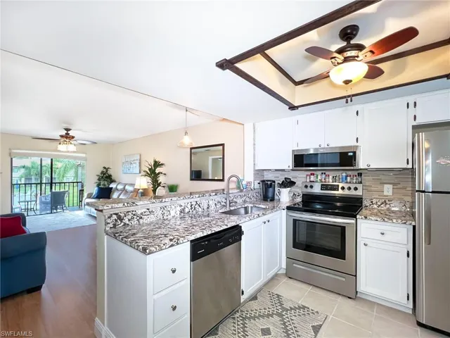 Kitchen featuring decorative backsplash, white cabinetry, sink, and appliances with stainless steel finishes