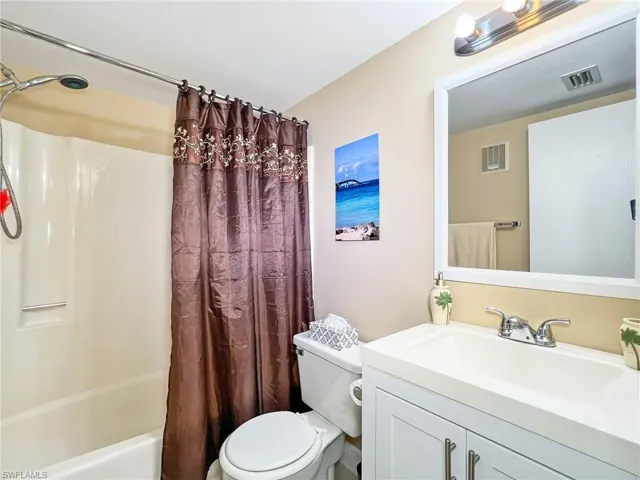Full bathroom with vanity, toilet, and shower / bathtub combination with curtain
