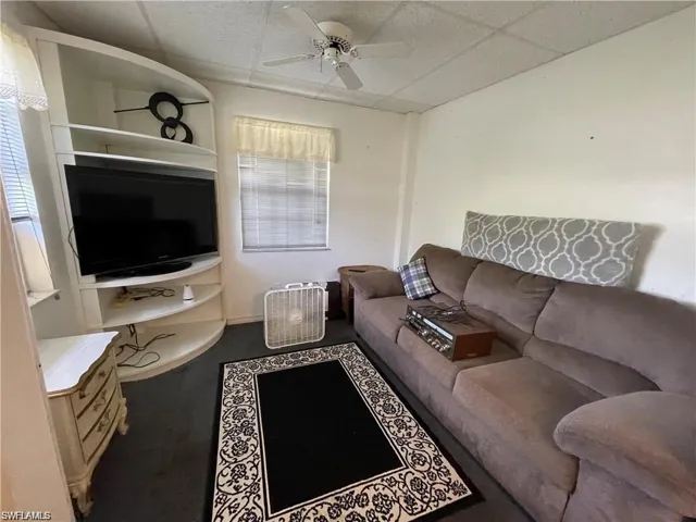 Living room featuring ceiling fan and a drop ceiling