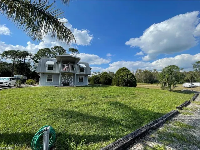View of front of home with a balcony and a front yard
