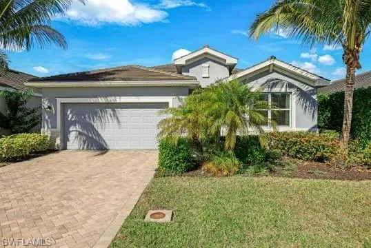 View of front of house featuring decorative driveway, a front yard, an attached garage, and stucco siding