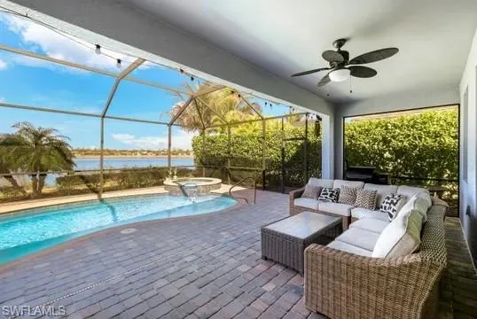Integrated pool / hot tub with a sunroom, an outdoor lounge area, glass enclosure, a patio area, and a water view