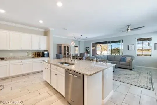 Kitchen featuring white cabinetry, stainless steel dishwasher, a ceiling fan, hanging light fixtures, and light stone counters