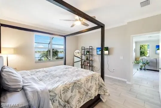 Bedroom with ceiling fan, light wood finished floors, and ornamental molding