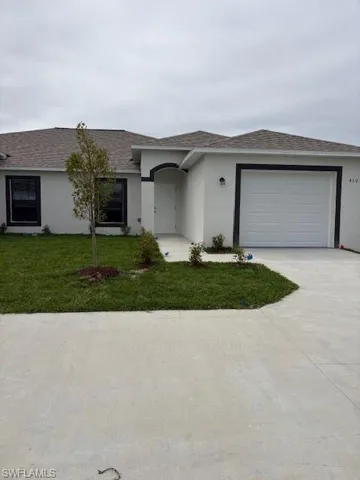 View of front of house featuring a front lawn, stucco siding, concrete driveway, a shingled roof, and a garage