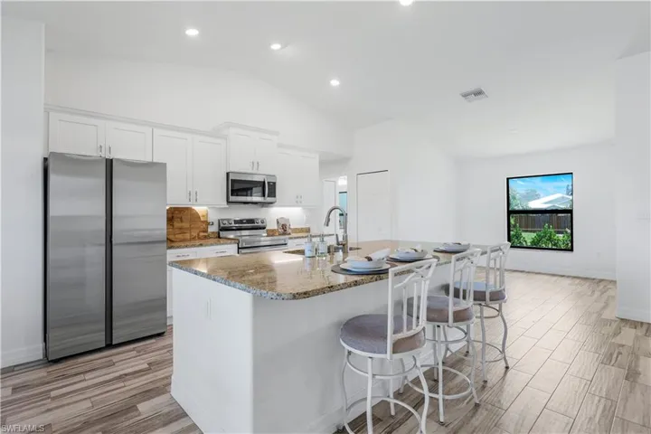Kitchen features stainless steel appliances, white cabinetry and large center island.