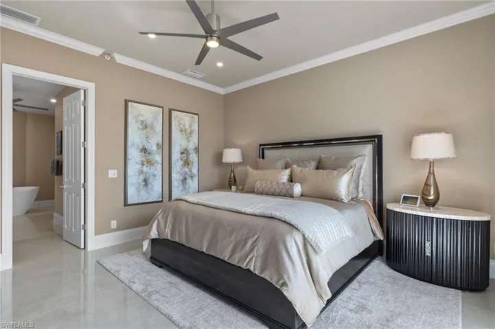 Bedroom featuring ensuite bathroom, ceiling fan, and crown molding