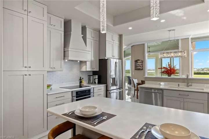 Kitchen featuring sink, tasteful backsplash, custom range hood, a breakfast bar, and appliances with stainless steel finishes