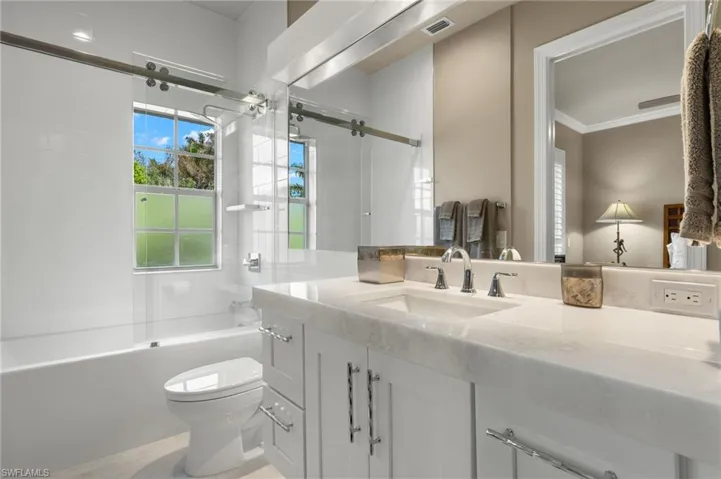 Full bathroom with toilet, vanity, bath / shower combo with glass door, and ornamental molding