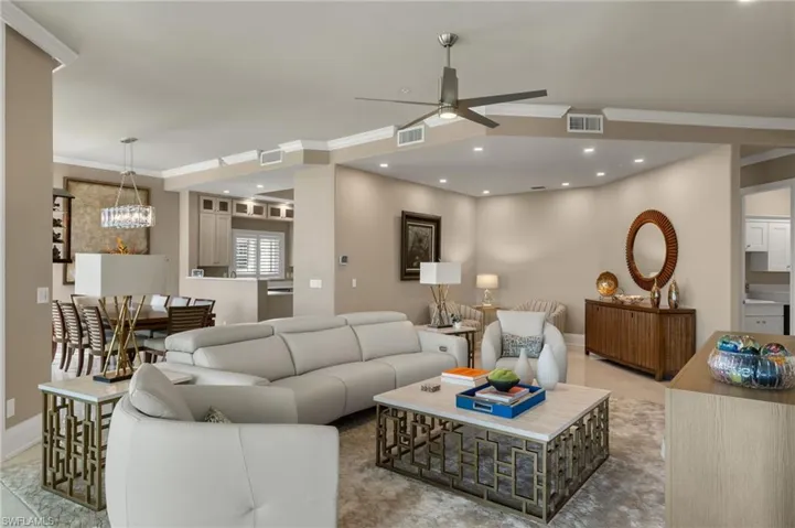 Living room featuring light tile patterned floors, ornamental molding, and ceiling fan with notable chandelier