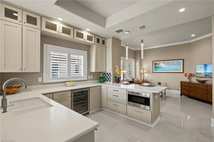 Kitchen featuring sink, wine cooler, kitchen peninsula, decorative light fixtures, and oven