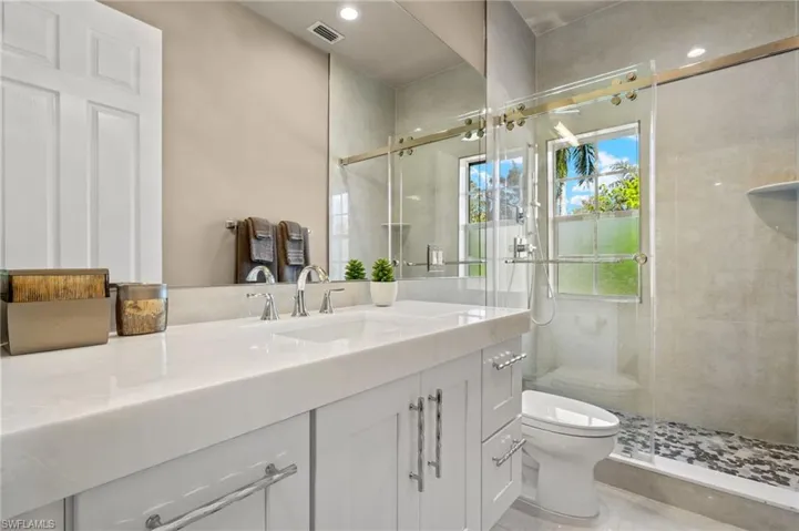 Bathroom with toilet, an enclosed shower, and vanity