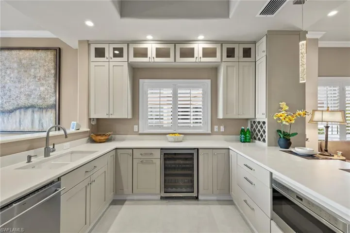 Kitchen featuring pendant lighting, beverage cooler, appliances with stainless steel finishes, and crown molding