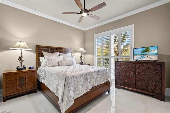 Bedroom with ornamental molding, light colored carpet, and ceiling fan