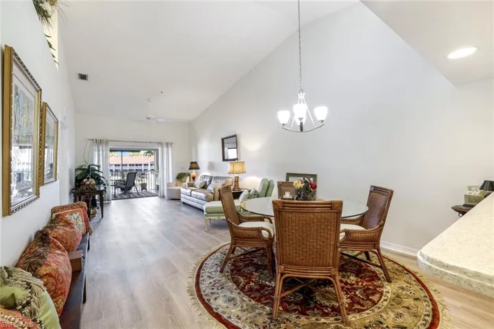 Dining space with lofted ceiling, light wood-style flooring, a chandelier, and a ceiling fan