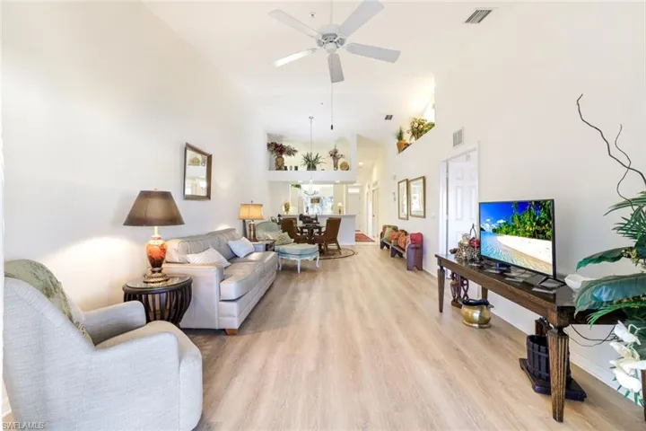 Living room with light wood-type flooring, a ceiling fan, and vaulted ceiling