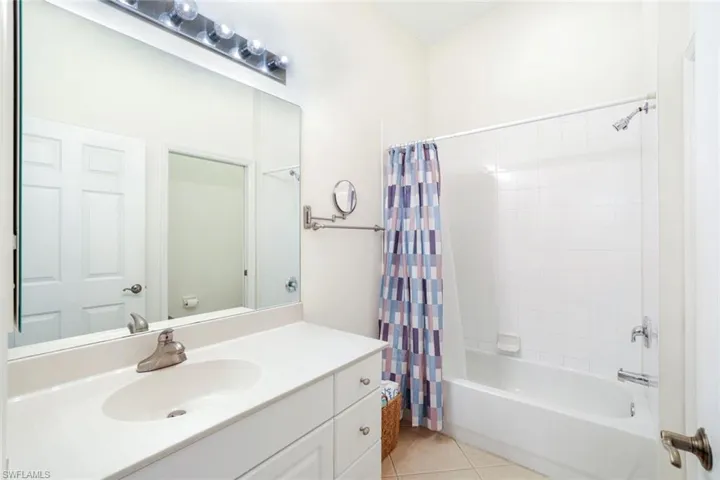 Bathroom featuring vanity, shower / bath combo with shower curtain, and light tile patterned floors