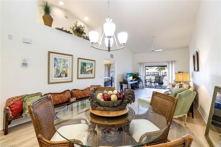 Dining room featuring lofted ceiling, a ceiling fan, light wood-style flooring, and a chandelier