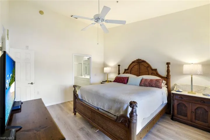 Bedroom featuring light wood-style floors, a high ceiling, a ceiling fan, and ensuite bath