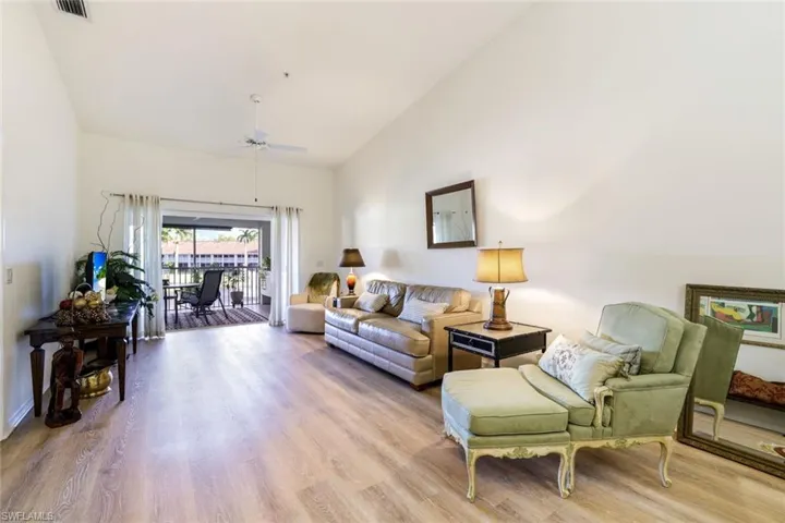 Living room with wood finished floors, vaulted ceiling, and a ceiling fan